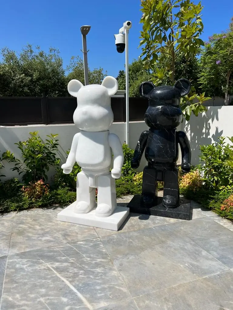 A white and a black bear sculpture on a garden patio