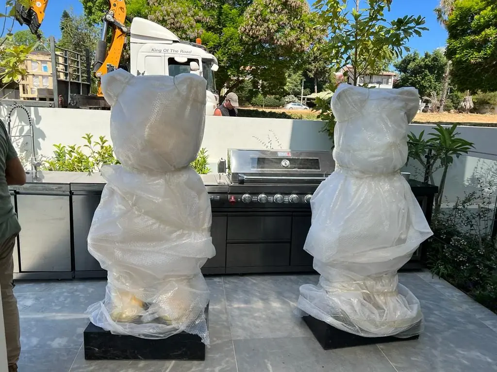 Two wrapped bear sculptures delivered to a terrace, with the crane truck behind
