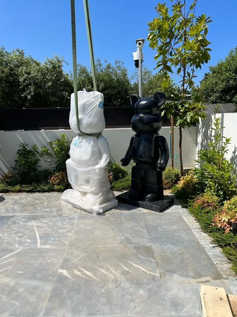 A wrapped bear sculpture and a black bear sculpture in a garden