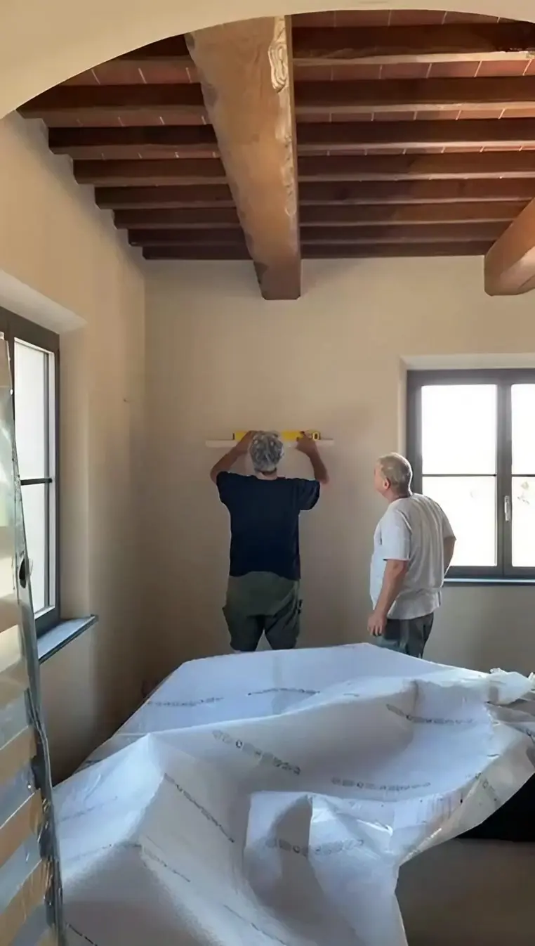 Two of our team installing artwork in a room, with packing material on the floor